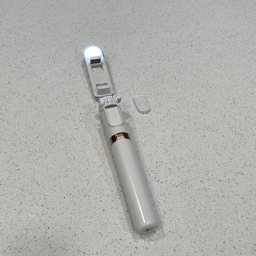 White selfie stick with charger and remote button control, rose gold detail